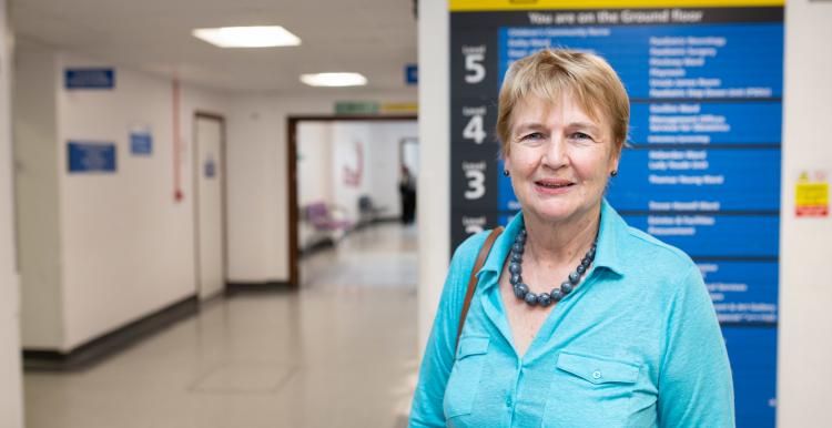 Woman standing in a hospital corridor in front of a sign