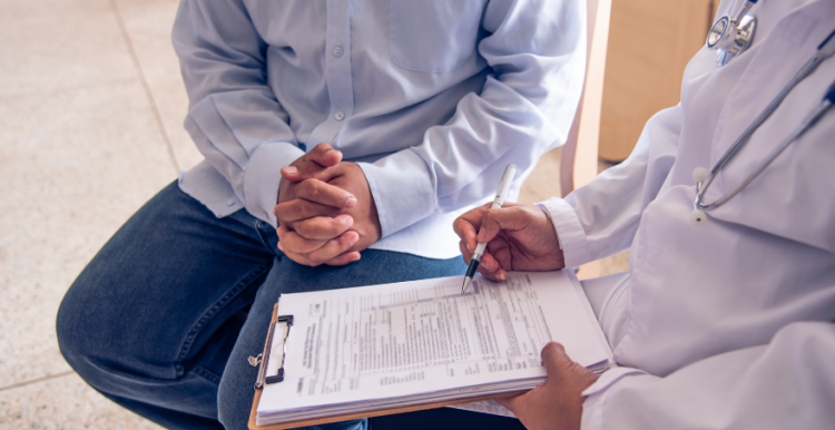 a doctor and a patient filling in a document, their heads not visible in the photo