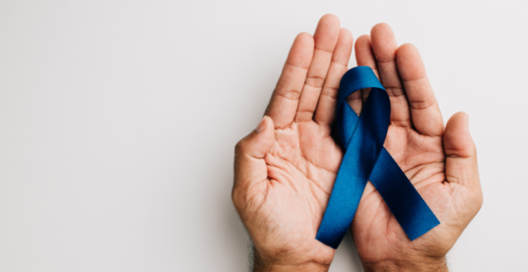 A hand holding a blue ribbon to symbolise men's health