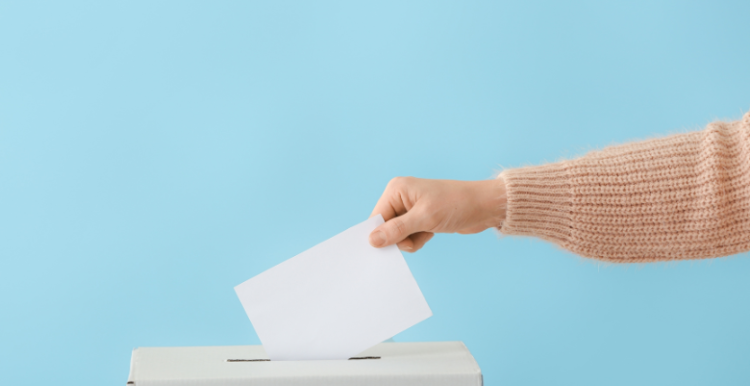 someone putting their vote in the ballot box