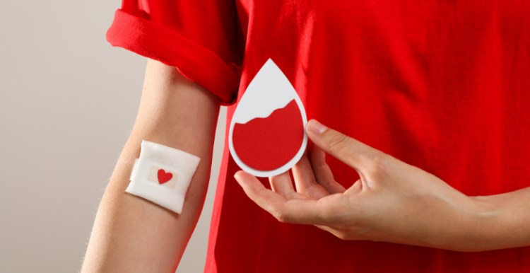 A person holding a card with an image symbolising blood after donating blood