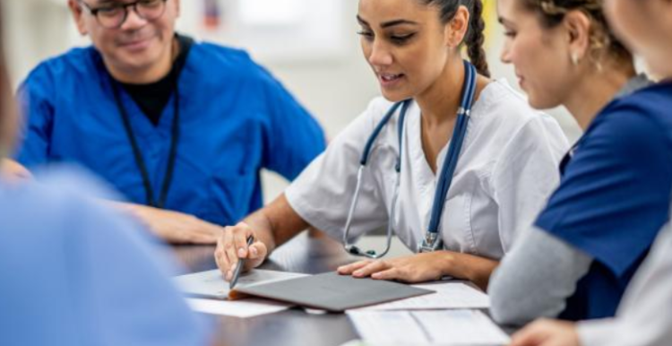 A picture showing a group of medical professionals having a discussion around a table.