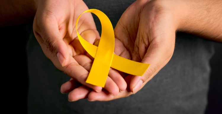 Picture of hands holding a yellow ribbon to represent world suicide prevention day.