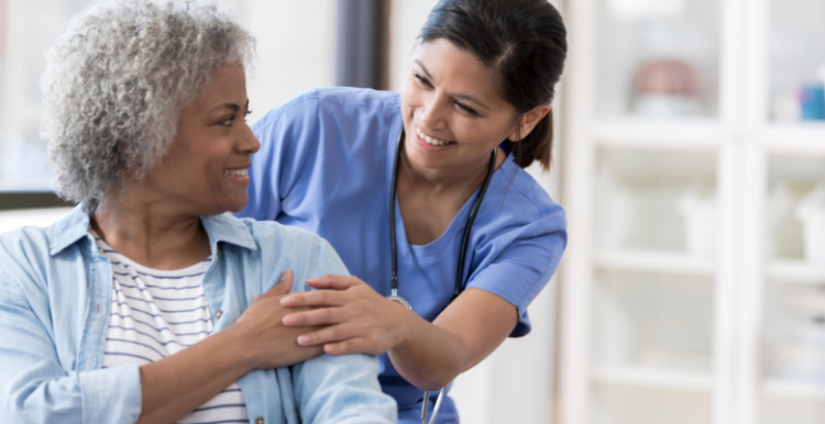 A doctor putting hand on the shoulder of a patient as they smile at eachother.