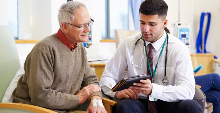 A male GP doctor holding a tablet and discussing a medical report with a male patient.