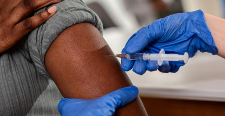 A black person receives a vaccine in their arms.