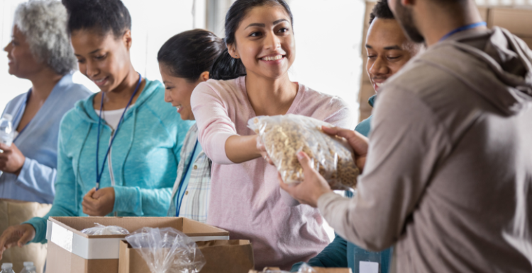 People volunteering at a food bank by handing out food.