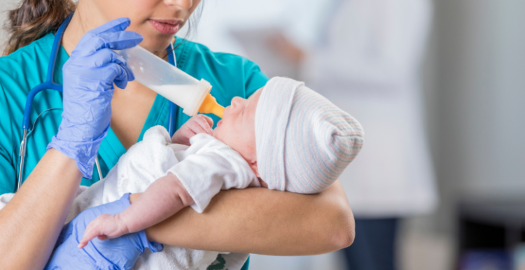Nurse feeds newborn baby a bottle of milk