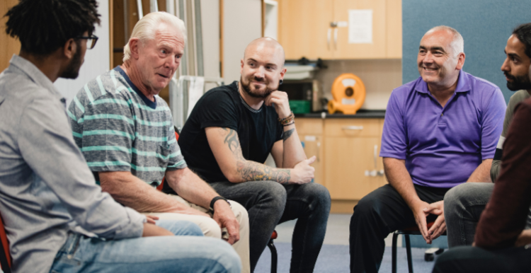 Men of different age groups and ethnicities sitting together in a support group