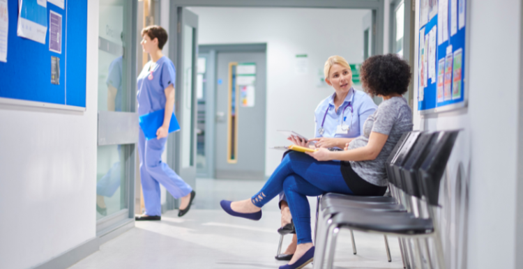 A female doctor talking to a woman in a hospital clinic waiting area
