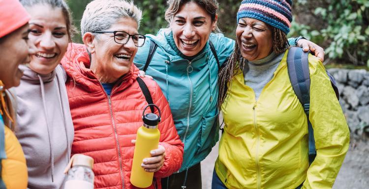 A group of women from different ages and ethnicities laughing together outside
