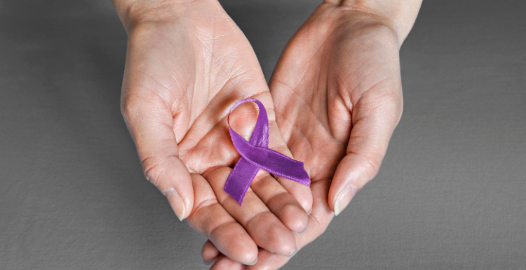 Two hands holding a purple ribbon to represent pancreatic cancer