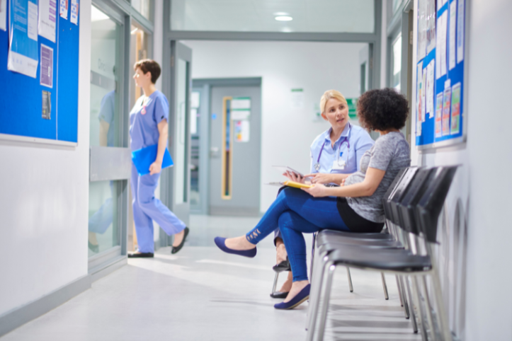 A female doctor talking to a woman in a hospital clinic waiting area