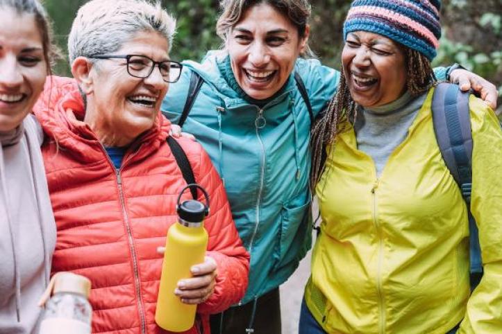 A group of women from different ages and ethnicities laughing together outside