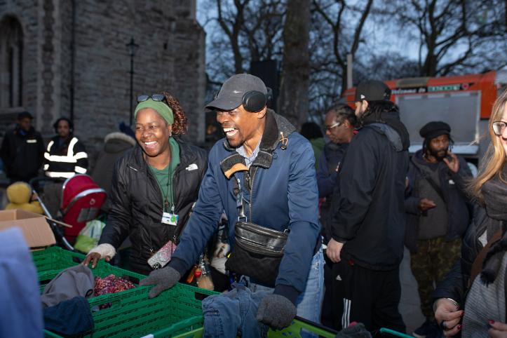 A black man and woman standing by two crates of donations as they volunteer