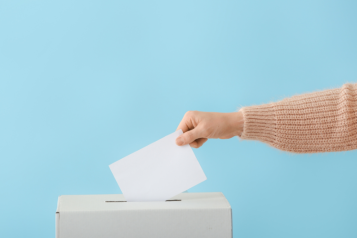 someone putting their vote in the ballot box