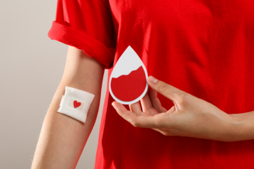 A person holding a card with an image symbolising blood after donating blood