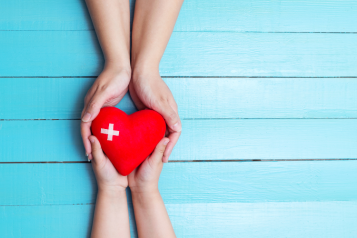 two pair of hands holding a 3D heart shape.
