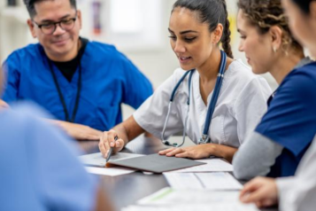 A picture showing a group of medical professionals having a discussion around a table.