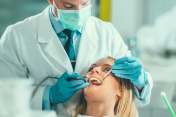 A male dentist doing a checkup on a female patient.