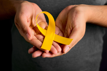 Picture of hands holding a yellow ribbon to represent world suicide prevention day.