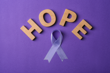 An image with a purple background, a purple ribbon and a letters spelling out the work HOPE.