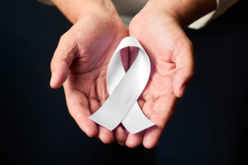 Two hands holding a white ribbon to raise awareness about violence against women and girls.