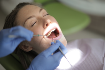 A patient opening her mouth for the dentist to do a check up on her teeth.