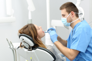 Male dentist doing a check up on a female patient in a clinic.