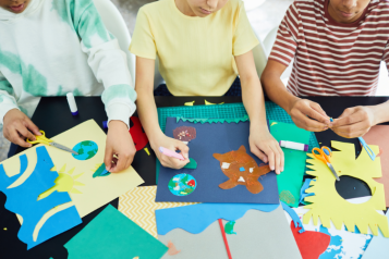 Three children colouring in and doing arts and crafts. 
