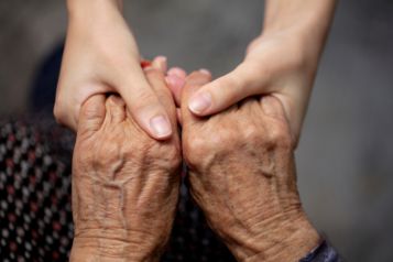 The hands of a young person holding an elderly person's hands.