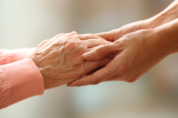 The hands of a young person holding an elderly person's hands.