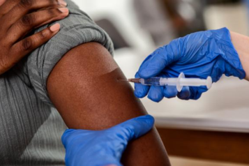 A black person receives a vaccine in their arms.