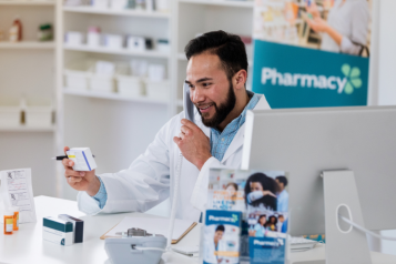 A male pharmacist on the phone whilst holding a medicine in his hands.
