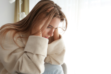 Sad woman with hands on head in room