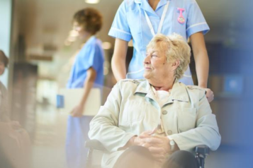 A nurse assisting a patient in a wheelchair in the hospital