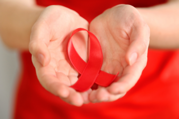 Hands holding a red ribbon which symbolises World Blood Cancer Day.