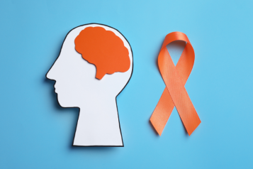An image of a human head card board cutout with an orange brain and ribbon on light blue background, to represent multiple sclerosis