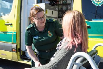 A paramedic assisting a patient out of the ambulance
