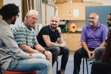 Men of different age groups and ethnicities sitting together in a support group