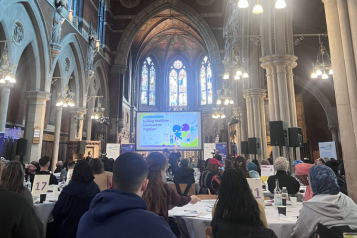 Attendees sitting in a hall looking at a screen during the community champions event