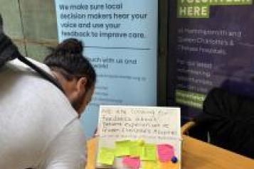 A man writing on a post it note at a hospital table