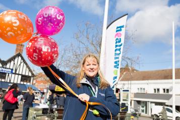 Healthwatch staff member holding balloons at a community event