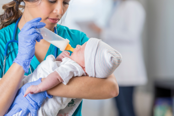 Nurse feeds newborn baby a bottle of milk