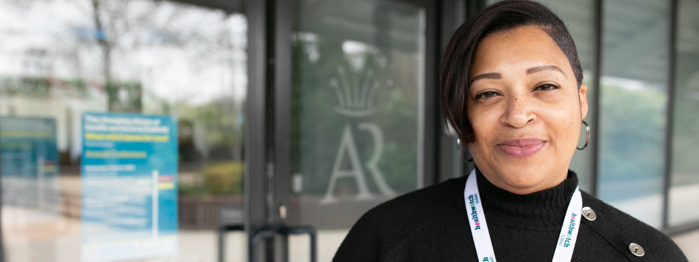 Woman wearing a Healthwatch lanyard smiling at the camera