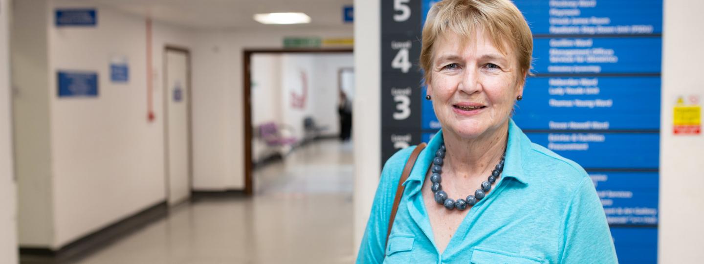 Woman standing in a hospital corridor in front of a sign