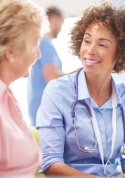 NHS doctor sitting next to a female patient and talking to them during their appointment.